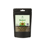 A black stand-up pouch of Brahmi tea with a clear window showing dried green-brown leaves inside. The front label is light green with the brand name 'Brahmi' and product details, set against a plain white background.